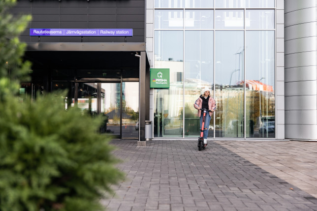 Tyttö sähköpotkulaudan kanssa Kupittaan rautatieaseman sisäänkäynnin luona.