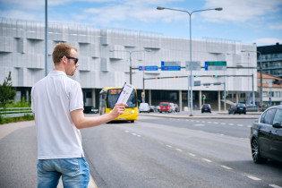 Mies viittilöi bussin pysähtymään teatterilippu kädessään.